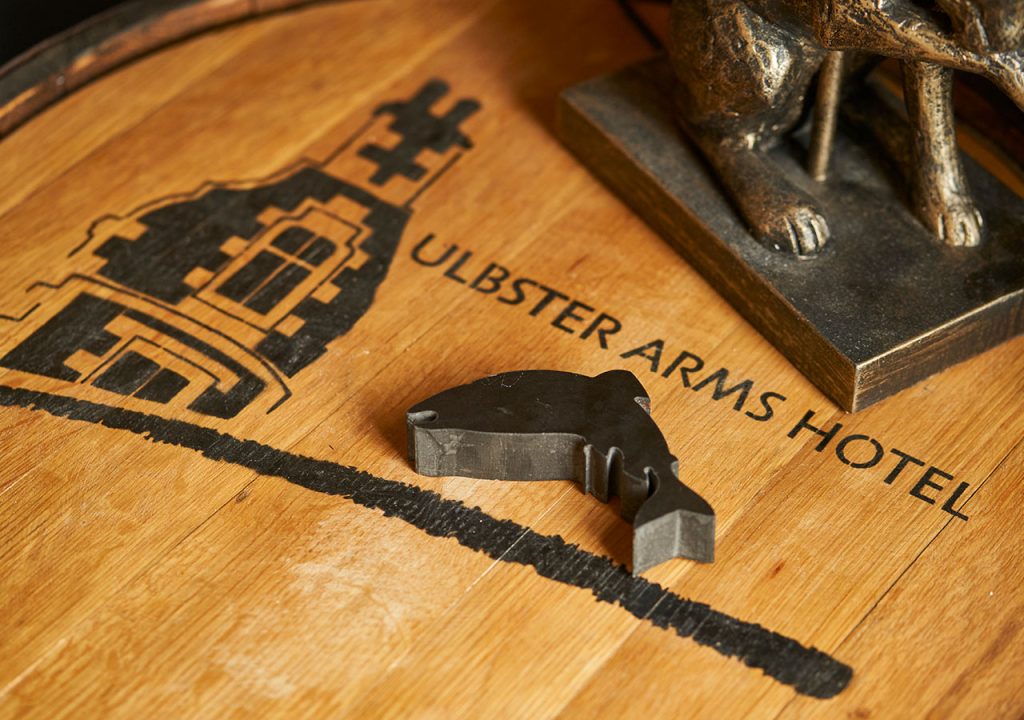 An fish decoration jumping a print on wood saying Ulbster Arms Hotel