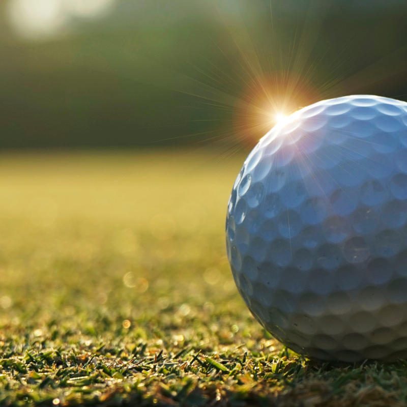 White golf ball near hole on green grass