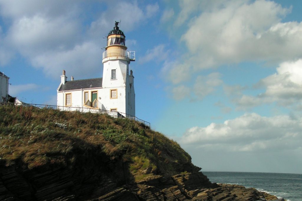 Scrabster Lighthose sitting at the top of a rugged rock face