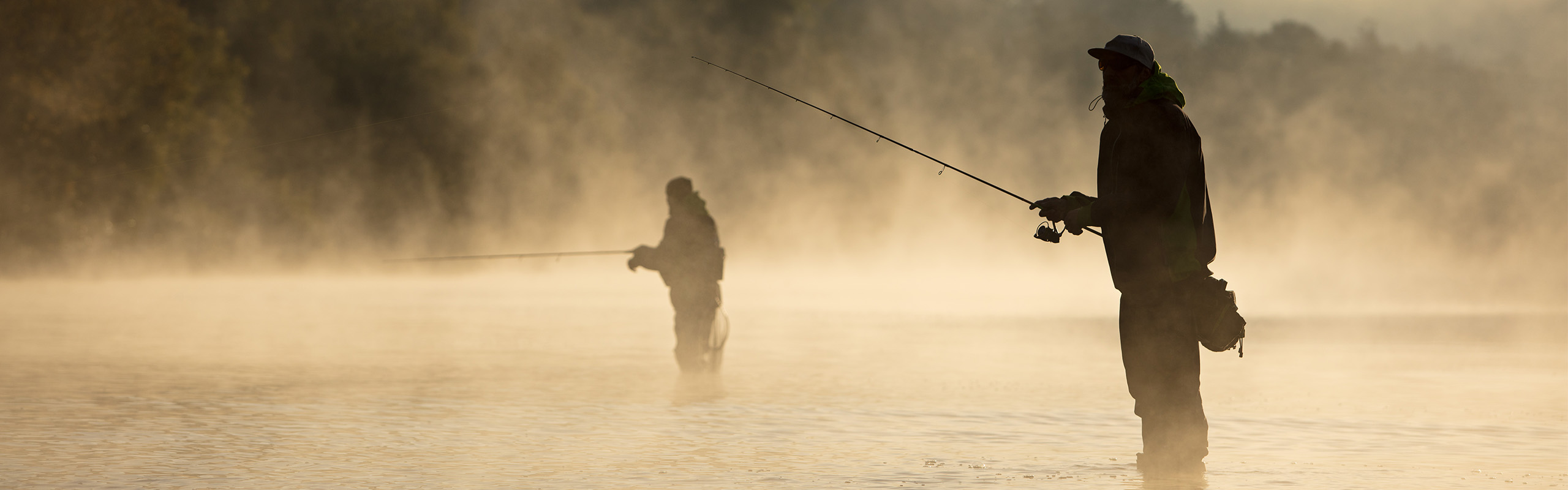 Two people fishing is a misty river