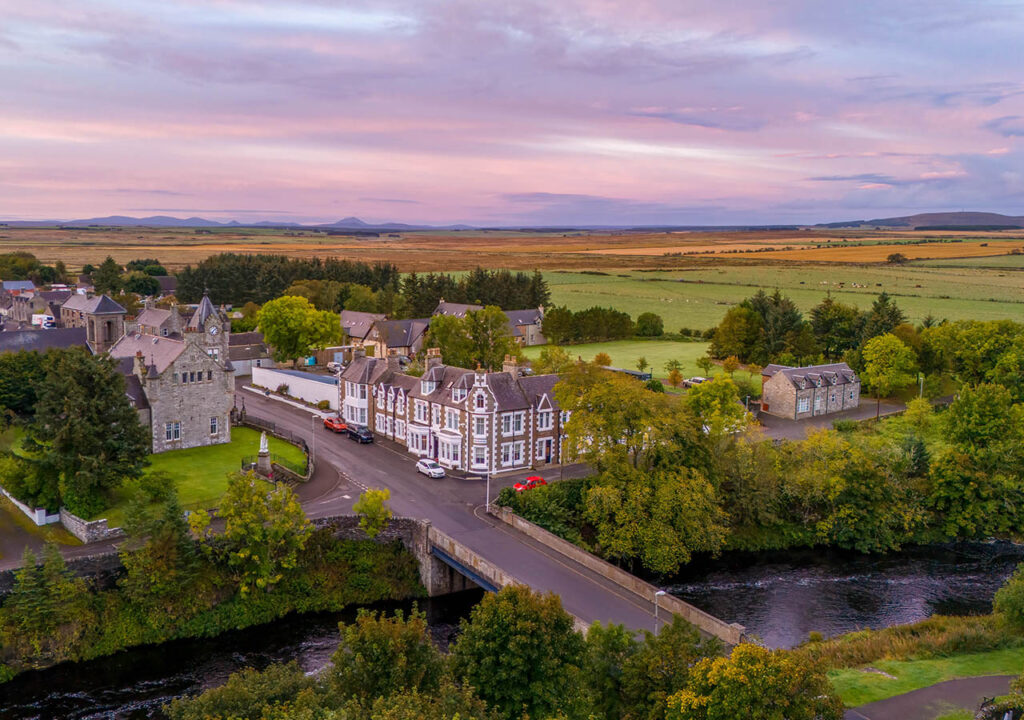 An aerial view of the Ulbster Arms Hotel in Halkirk showing its rural landscape and location at sunset