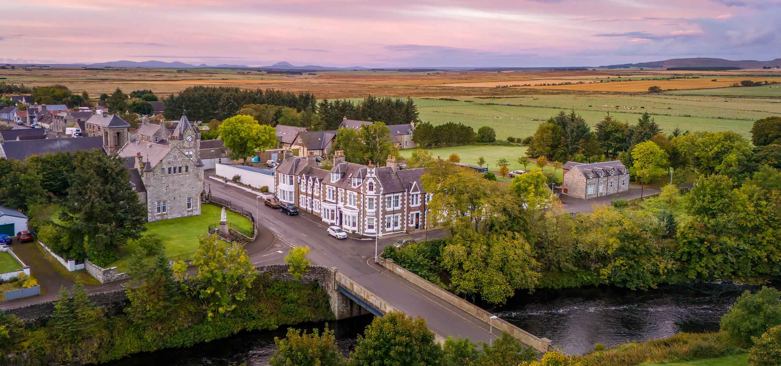 An aerial view of the Ulbster Arms Hotel in Halkirk showing its rural landscape and location at sunset