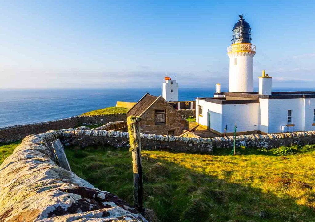 Dunnet lighthouse in the north of Scotland with a blue sky.