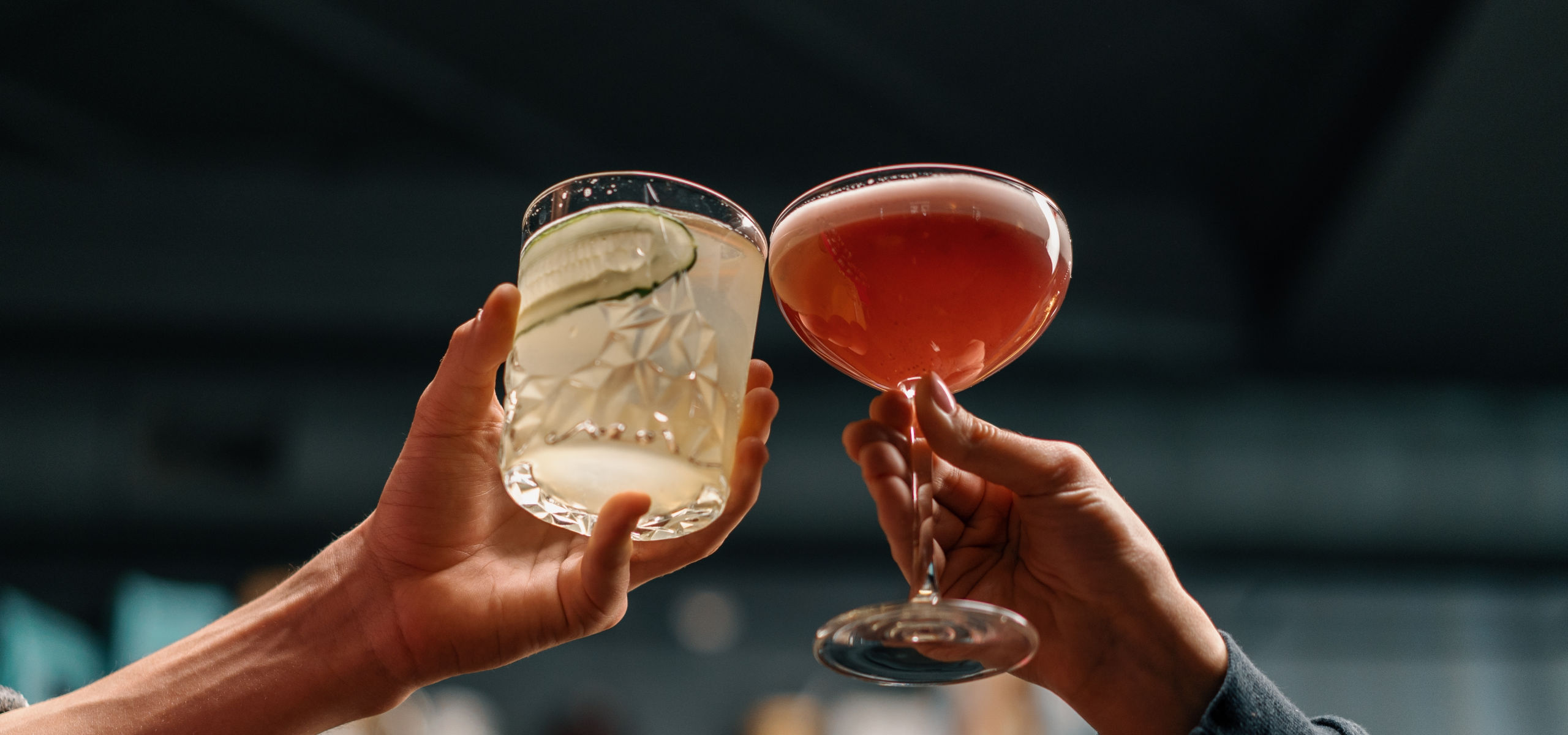 Close up of two people cheering cocktails in bar