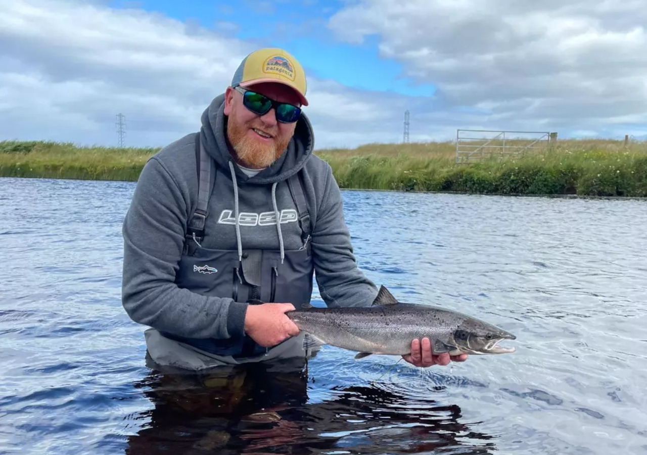 Man holding a fish on a River Thurso fishing trip