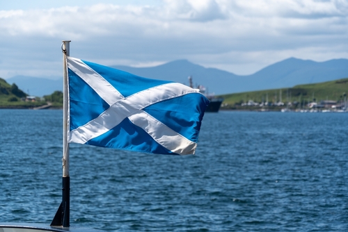 The Scottish Flag flying on a windy day on a flag pole on a Scottish boat.