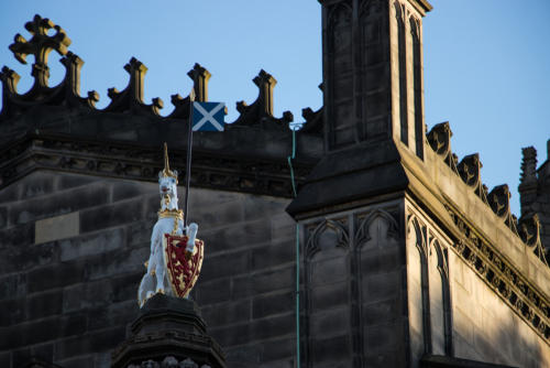 A unicorn statue sits proudly on top of an old Scottish castle.